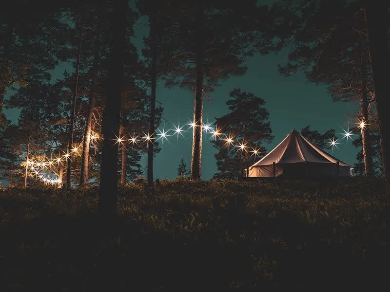 Canvas glamping tent set up with a bed and outdoor seating