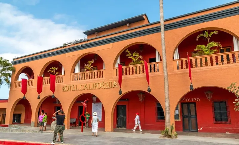Main street in Todos Santos with palms, painted storefronts, and dry Baja hills nearby