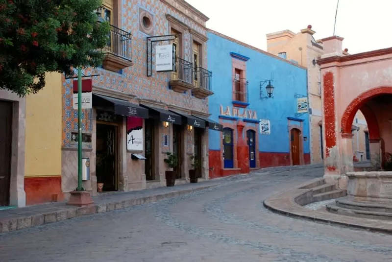 Bernal town center with stone streets and Peña de Bernal behind rooftops in rainy season