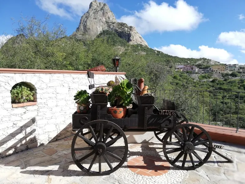 Peña de Bernal rock monolith above green hills after August rain