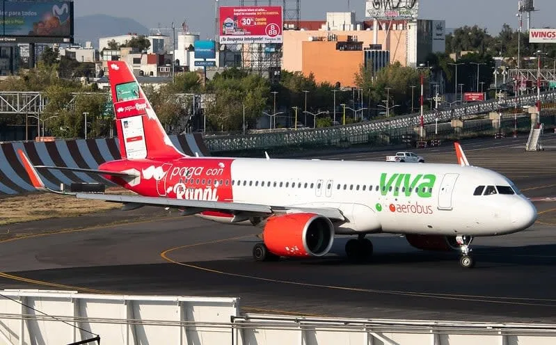 Viva Aerobus plane parked beside airport service vehicles