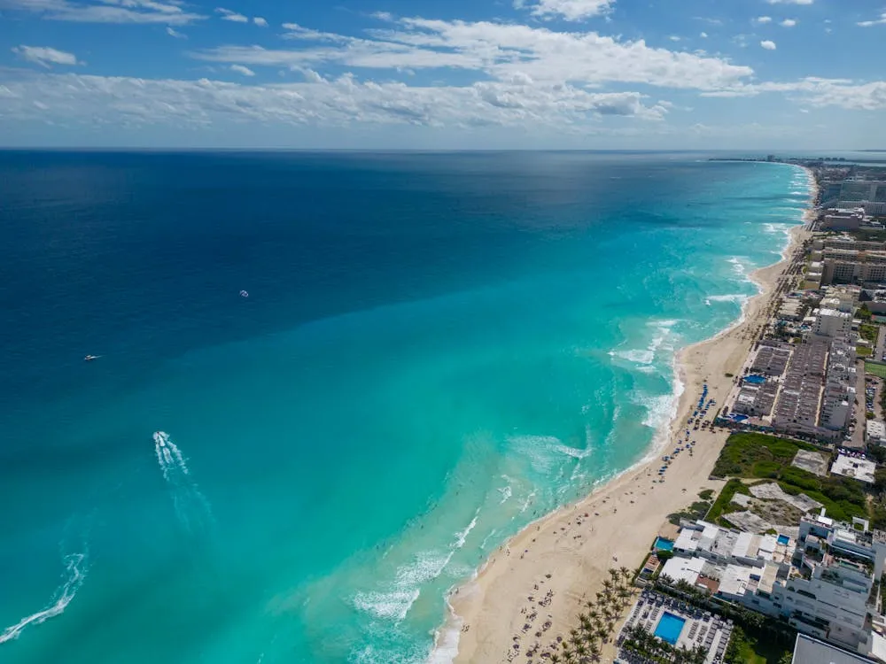 Aerial view of Cancun Hotel Zone with turquoise Caribbean water, white sand, and resort towers