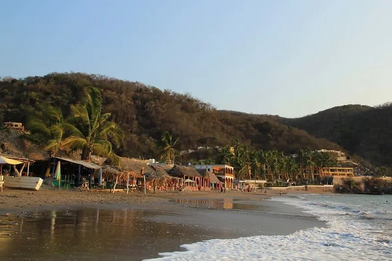 Protected rock cove at Cuastecomates with calm water and palapas