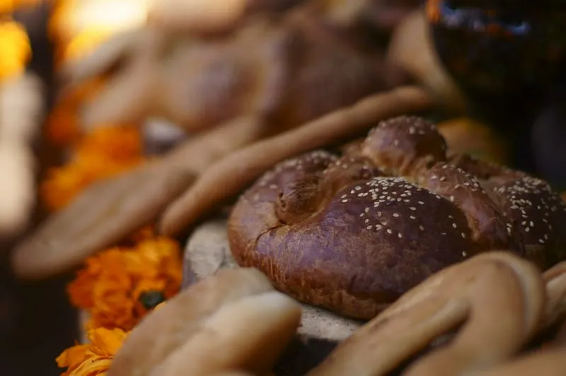 Round pan de muerto with sugar topping on a white plate
