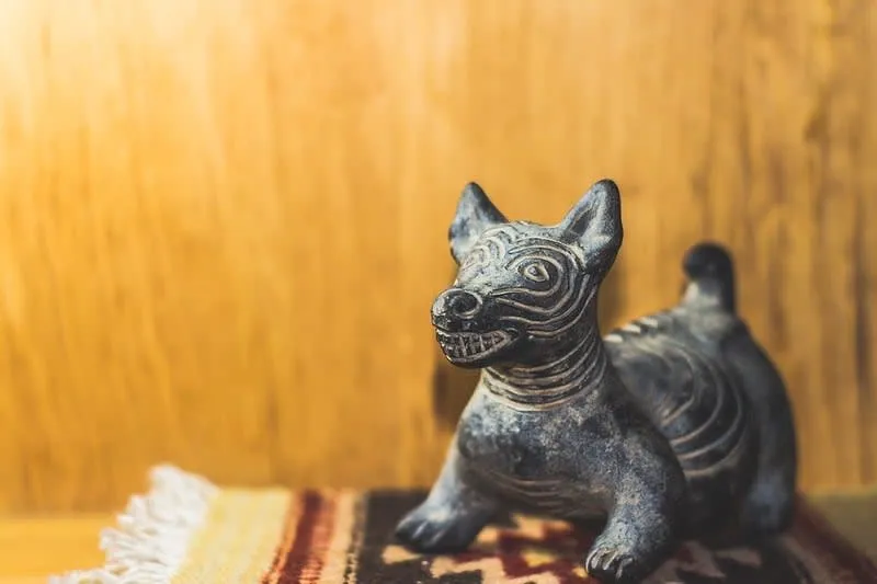 Xoloitzcuintli dog figure beside candles on a Day of the Dead display