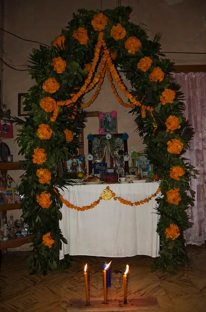 Marigold altar arch framing candles and papel picado