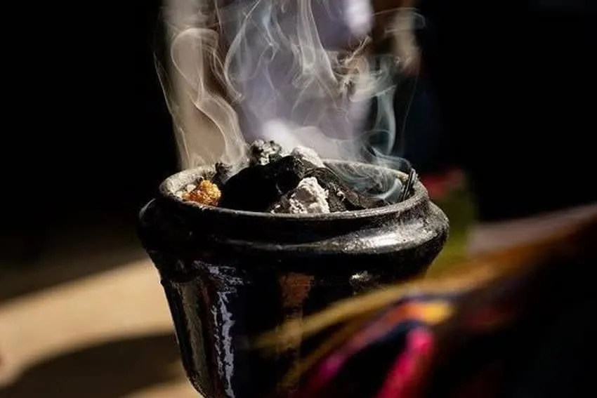 Copal incense smoke rising beside candles and marigolds