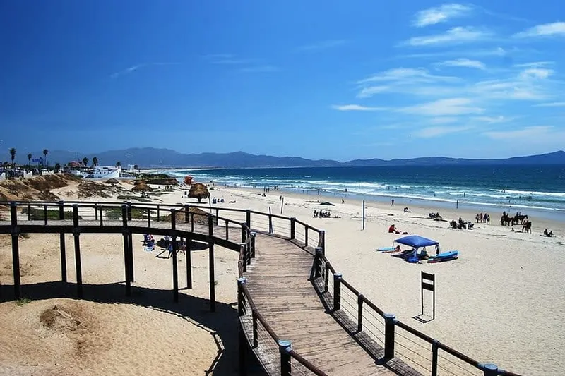 Sunny winter beach near Ensenada with calm Pacific water and a wooden boardwalk