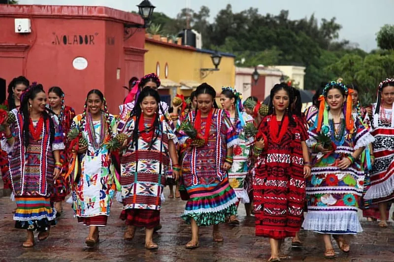 Oaxaca dancers in embroidered clothing performing on a bright stage
