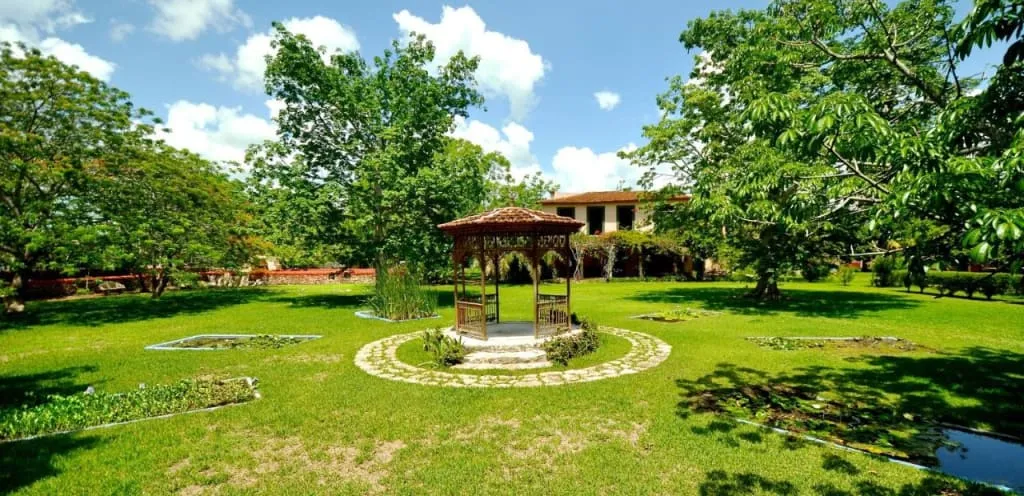 Long Yucatan hacienda facade with arches, chapel details, and garden paths