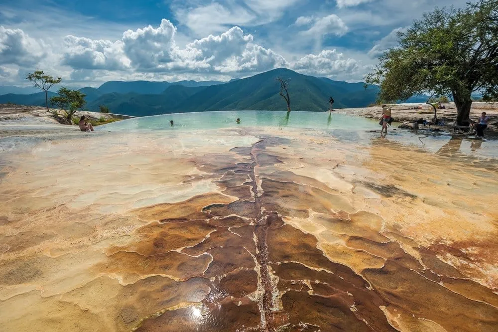 Hierve el Agua mineral springs in Oaxaca — the petrified waterfall formations cascade down the cliff edge with natural infinity pools above and the Oaxacan valley below