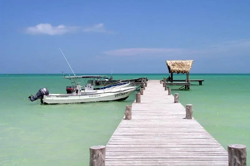 Fishing boats pulled onto the sand beside calm water on Holbox