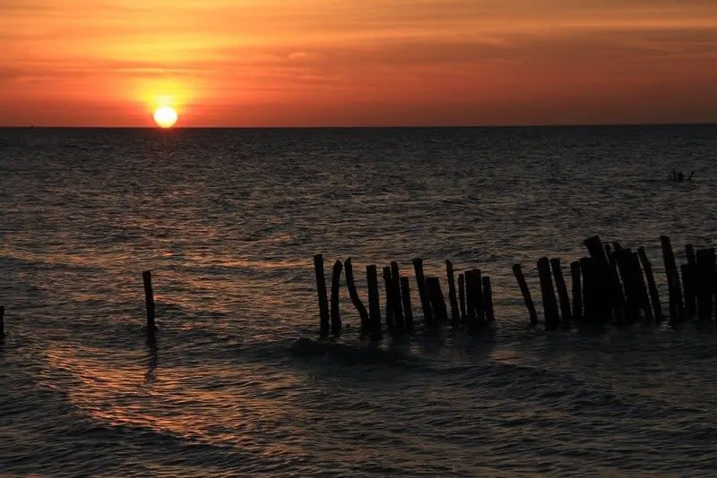 Vibrant sunset over Holbox Island with orange and pink sky reflected in the shallow turquoise water