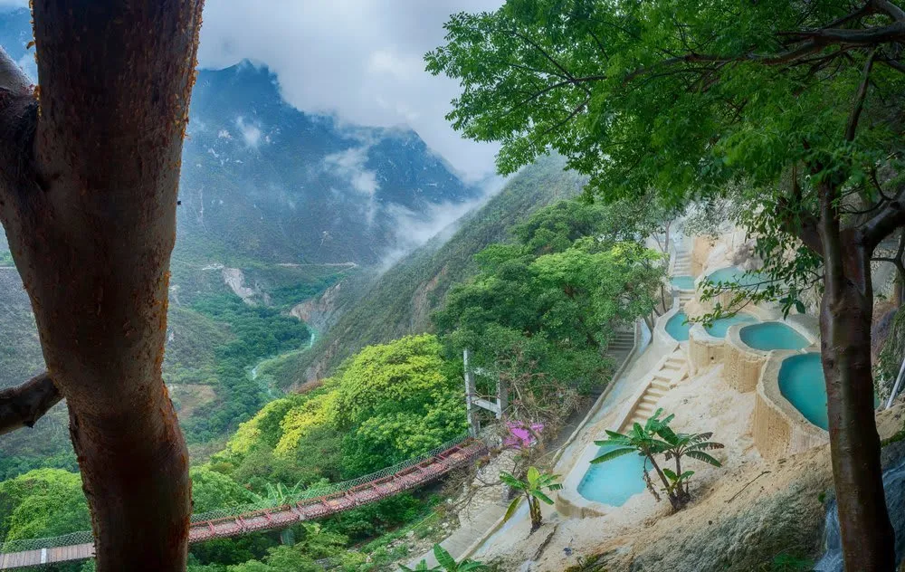 Thermal river flowing through the Grutas de Tolantongo canyon in Hidalgo, Mexico — terraced pools and cave entrance