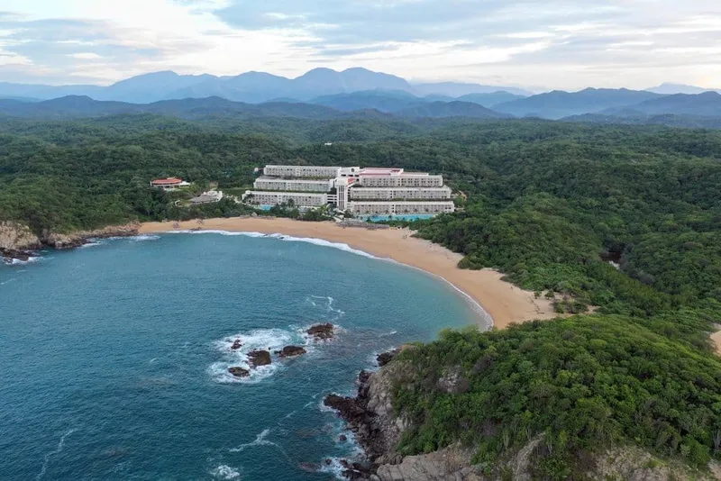 Quiet Huatulco beach with pale sand, palms, and calm Pacific water