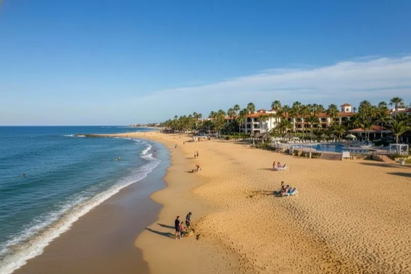 Playa El Palmar shoreline with Ixtapa resort towers and green rainy-season hills