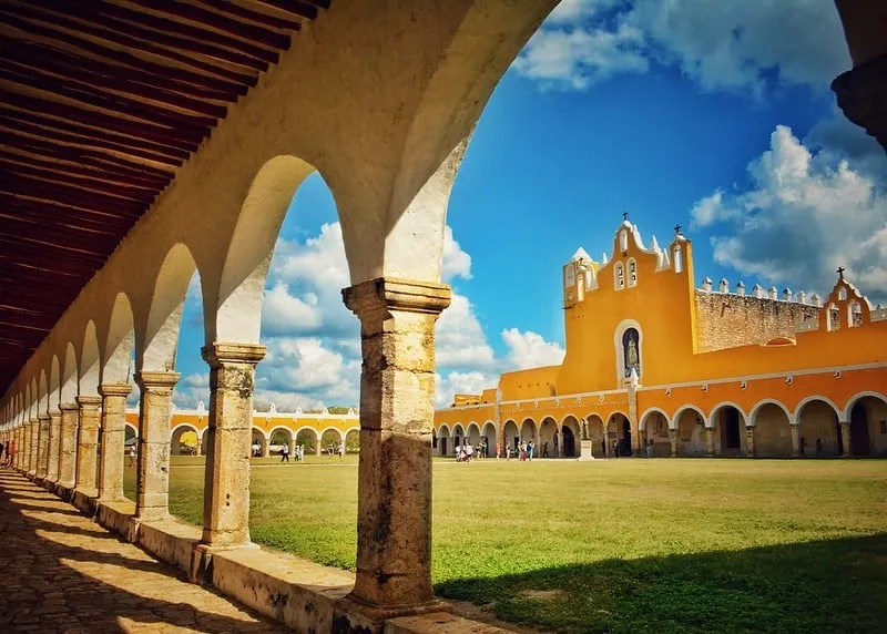 Yellow colonial facades and a quiet stone street in Izamal under bright Yucatan sun