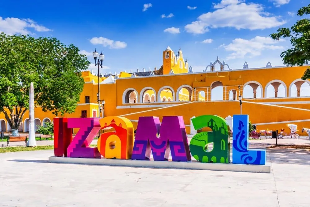 Colorful Izamal letters and plaza beside yellow arcades