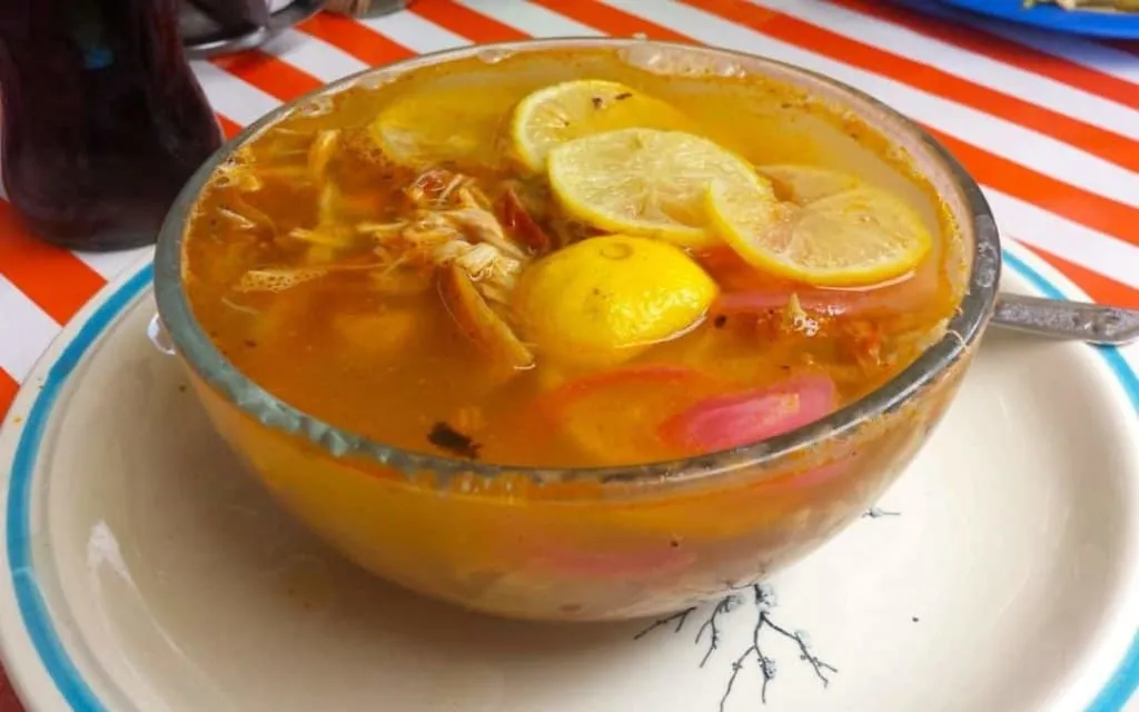 Sopa de lima — Yucatan lime soup with shredded chicken, fried tortilla strips, and fresh lime in a clear broth