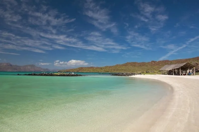 Clear blue water curling along a rocky Baja shoreline below dry desert slopes