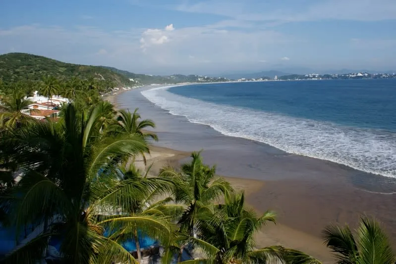 La Boquita Beach with calm Santiago Bay water and seafood palapas