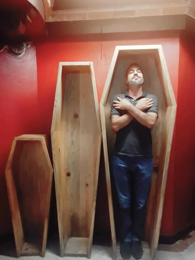 Visitor standing inside a wooden coffin-shaped museum display