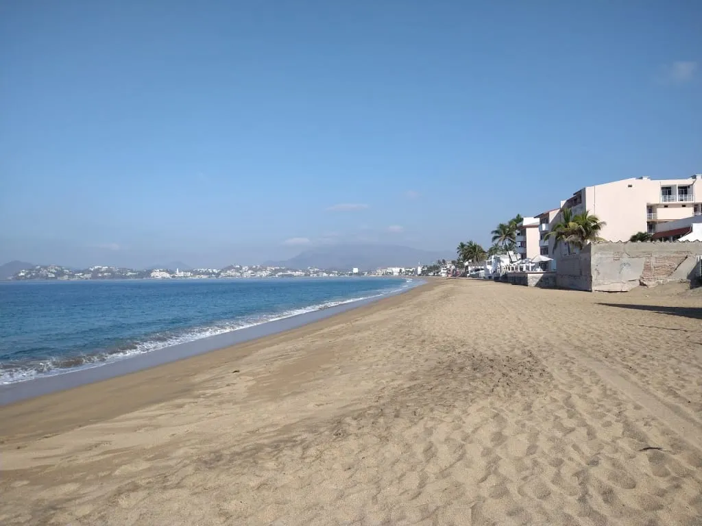 Playa Azul shoreline in Manzanillo with palms, dark sand, and Pacific waves in March