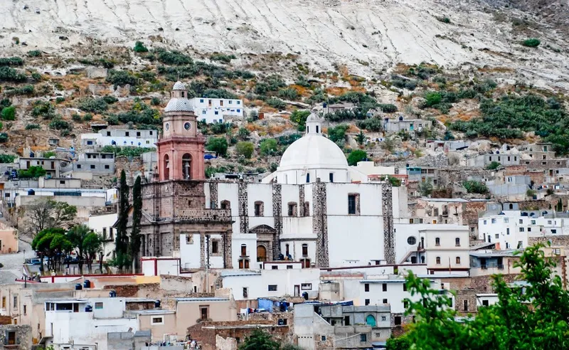 Adobe rooftops and cactus-covered hills around Real de Catorce under dry May light