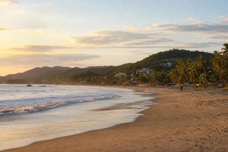 Broad San Pancho beach at sunset with Pacific waves and palm-lined sand