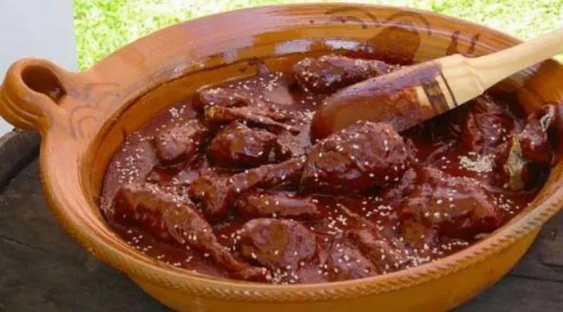 Traditional mole sauce being prepared in a clay pot over a wood fire in Mexico
