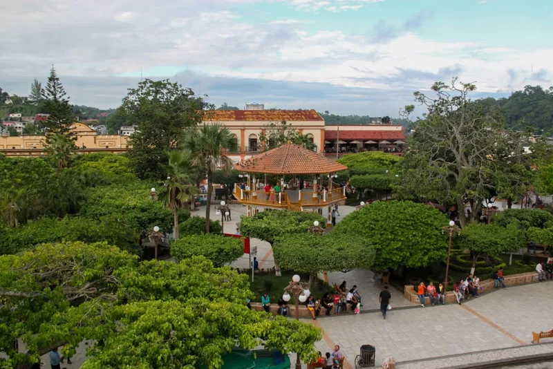 Papantla plaza garden with benches, trees, and colorful buildings around the square