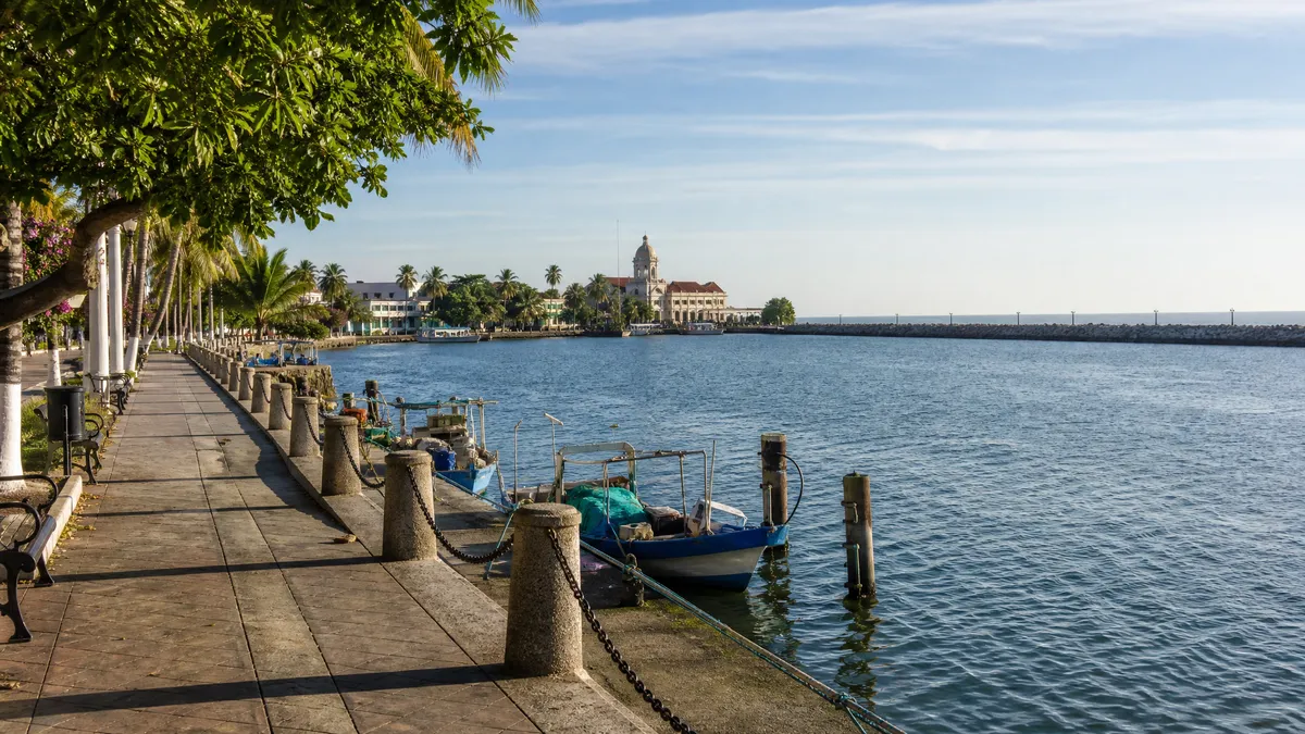 Tampico waterfront promenade with palm trees, lagoon reflections, and warm late-autumn light