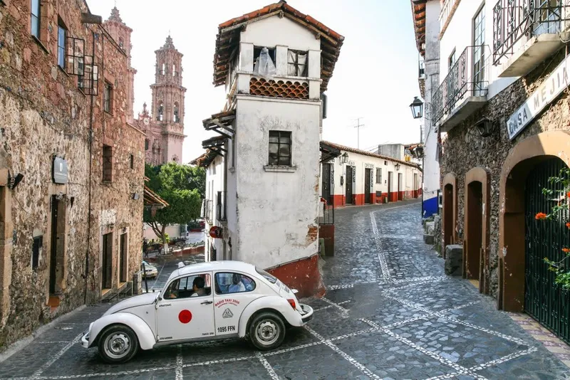 Steep cobblestone lane lined with white houses in Taxco, Guerrero