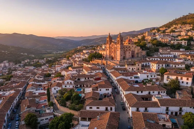 White hillside houses and Santa Prisca church rising above green June hills in Taxco