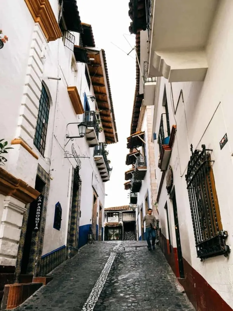 Steep cobblestone street in Taxco lined with white houses and red-tile roofs
