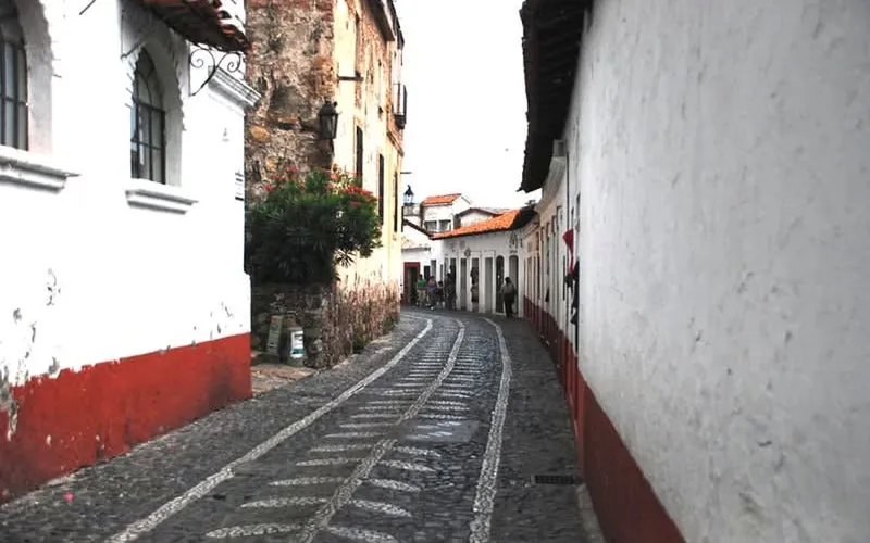 Steep Taxco streets in October with cobblestones, white houses, and late rainy-season walking conditions