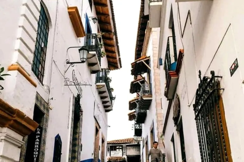 White Taxco houses and Santa Prisca set against green rainy-season hills