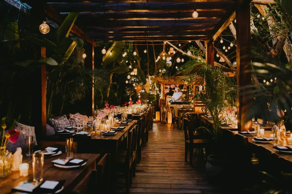 Open-air Tulum beach restaurant tables set near palms and white sand