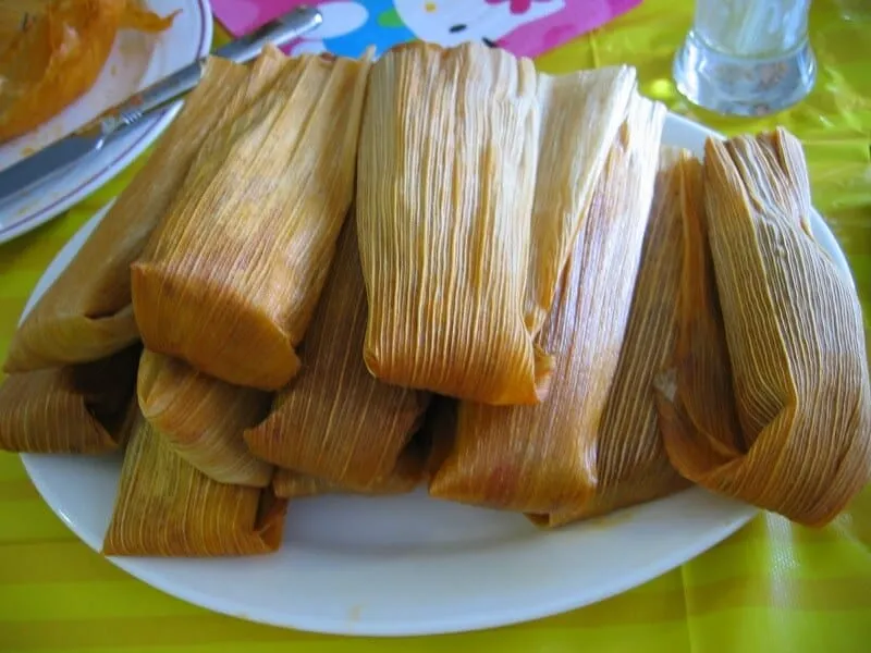 Corn-husk and banana-leaf tamales arranged on a plate