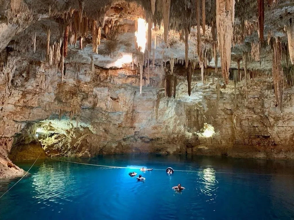 Underground cave cenote near Valladolid with stalactites and light beam through ceiling