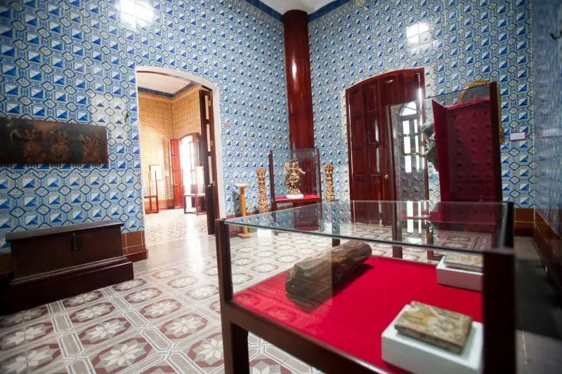 Museum room with blue patterned tile walls and glass display cases