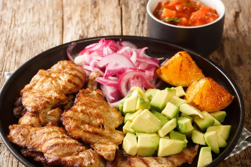 Poc chuc — thinly sliced pork marinated in sour orange and grilled over charcoal, served with black beans in Yucatan