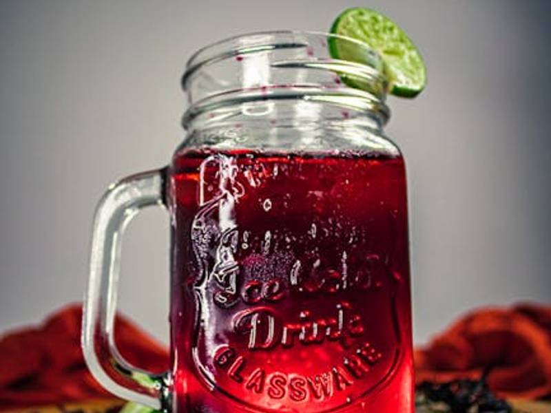 Colorful aguas frescas including red agua de jamaica and golden tamarindo in traditional glass containers