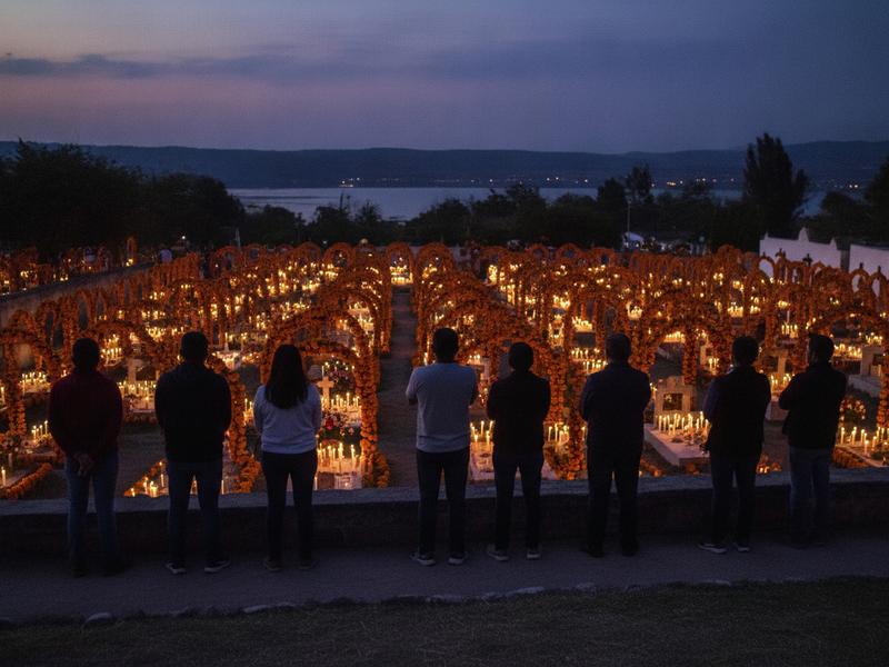 Visitors approaching candlelit Tzintzuntzan cemetery at blue hour