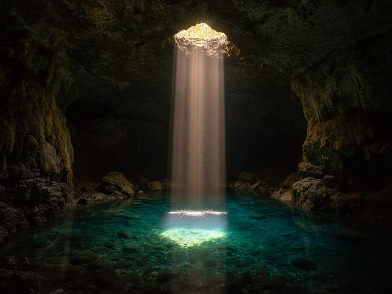 Dramatic light rays streaming through cave ceiling at Puente de Dios