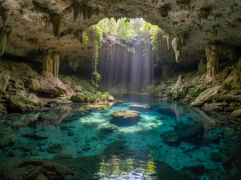 Ancient Maya pyramid at Chichen Itza with dramatic sky, representing the connection between Maya architecture and cenotes
